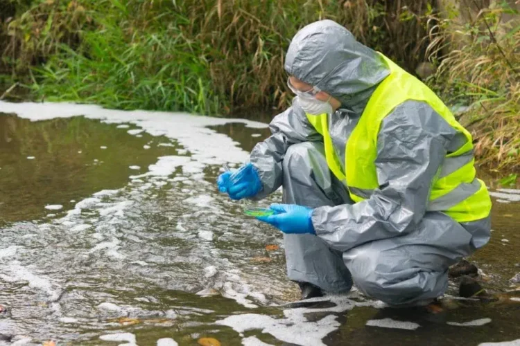 scientist in a protective suit and mask, collects legionella samples from the pond in a Petri dish